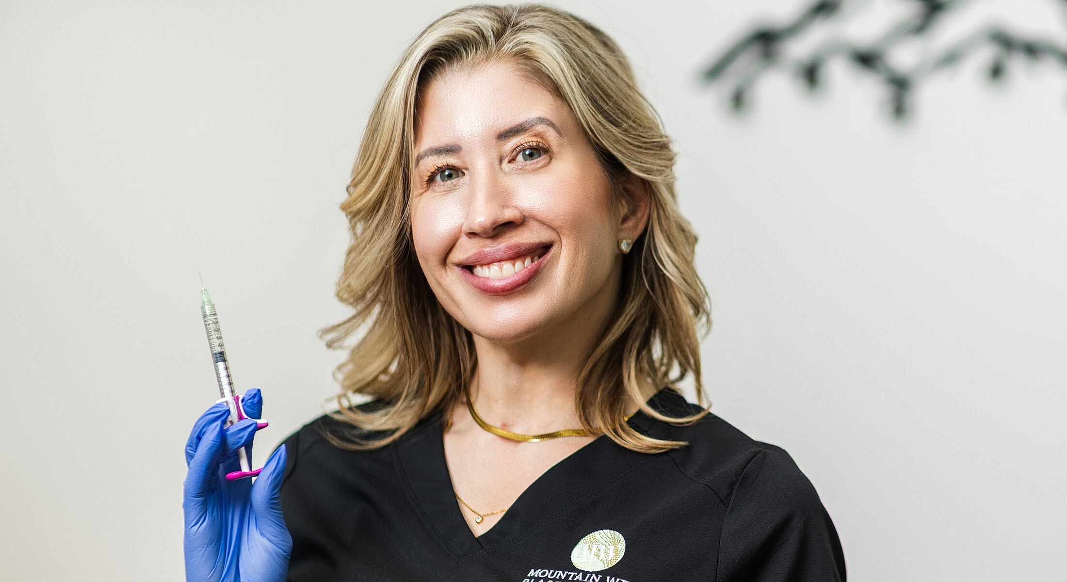 Professional holding a syringe and smiling confidently.