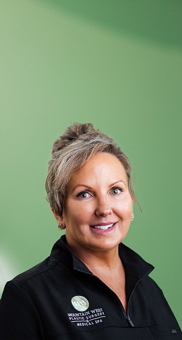 Smiling professional in medical attire against green backdrop.